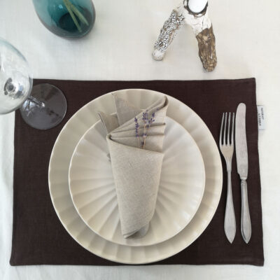 Brun bordstablett i linne dukat med porslin och bestick och naturfärgad linneservett.
