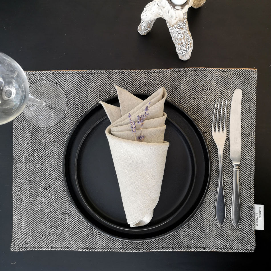 bordstablett i linne med fiskbensmönster dukat med porslin och bestick samt naturfärgad servett.