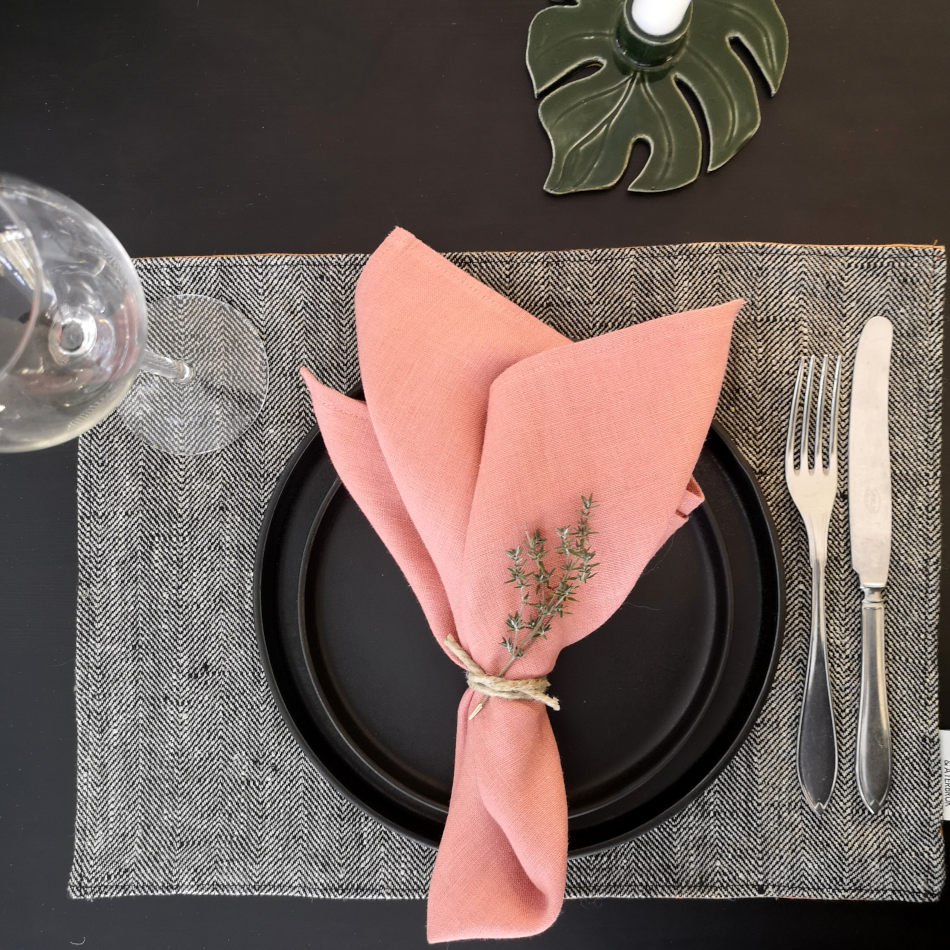bordstablett i linne med fiskbensmönster dukat med porslin och bestick samt rosa servett.