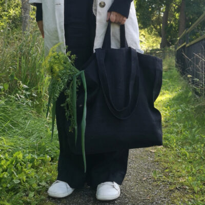 svart väska i grovt linne med grönsaker i väskan