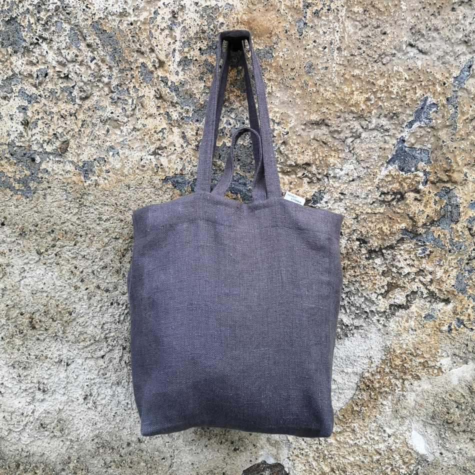 grå väska i linne hängandes på en krok på en stenvägg.