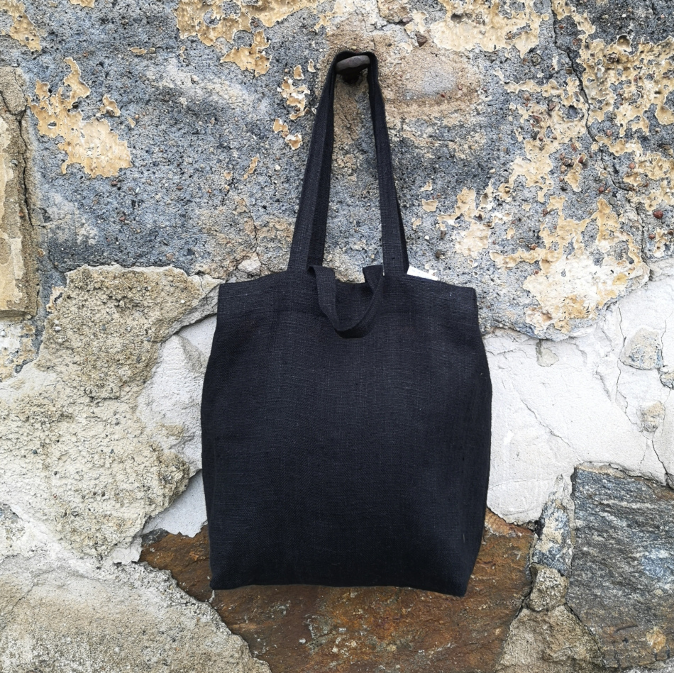 svart väska i linne hängandes på en krok på en stenvägg.